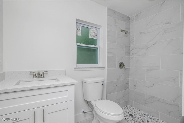 full bath featuring a tile shower, vanity, and toilet