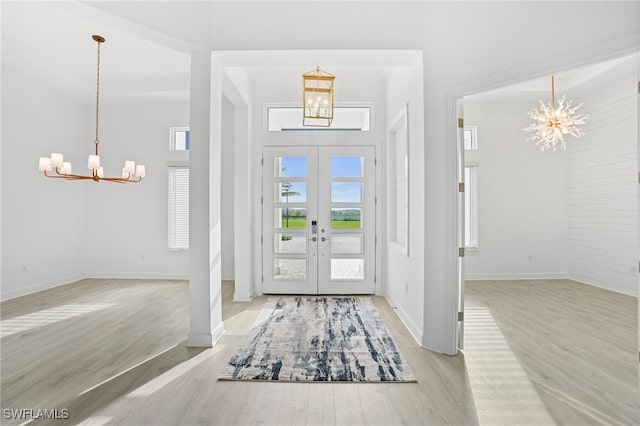 entryway featuring a notable chandelier, french doors, baseboards, and wood finished floors