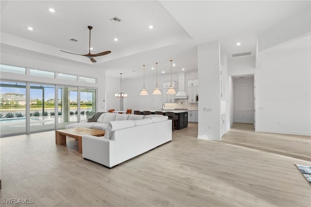 living room featuring light wood finished floors, a ceiling fan, visible vents, and recessed lighting