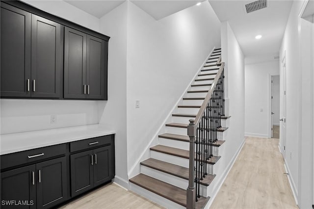 staircase featuring recessed lighting, baseboards, visible vents, and wood finished floors