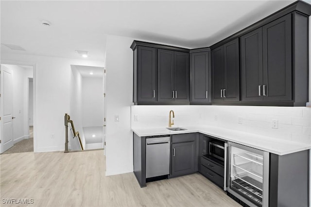 kitchen with a sink, light wood-style flooring, light countertops, and beverage cooler