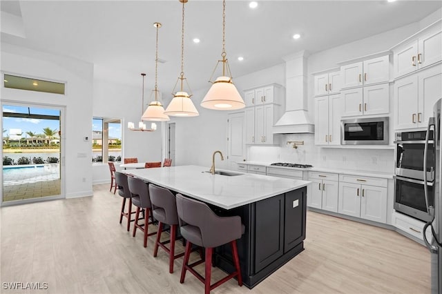 kitchen with built in microwave, light wood-style flooring, a sink, stainless steel double oven, and tasteful backsplash