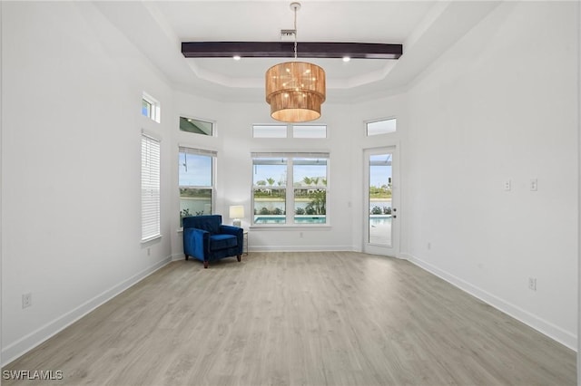 spare room with baseboards, beam ceiling, a high ceiling, and wood finished floors