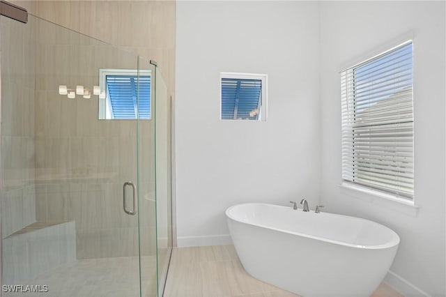full bath with baseboards, a soaking tub, plenty of natural light, and a shower stall