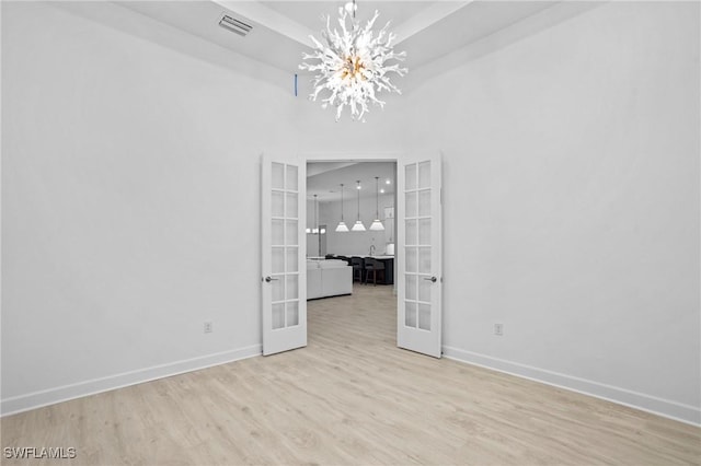 unfurnished room with baseboards, french doors, visible vents, and wood finished floors