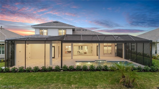 back of property at dusk with a yard, an outdoor pool, a patio area, stucco siding, and a lanai
