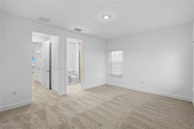 unfurnished bedroom with ensuite bath, visible vents, baseboards, and carpet floors