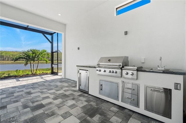 view of patio / terrace featuring a sink, area for grilling, glass enclosure, a water view, and an outdoor kitchen