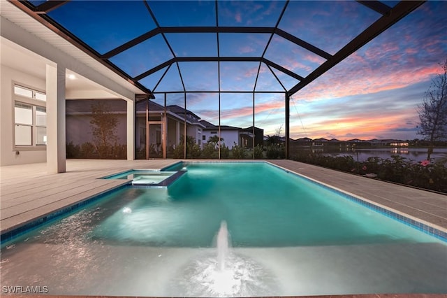 pool at dusk featuring a pool with connected hot tub, a lanai, and a patio