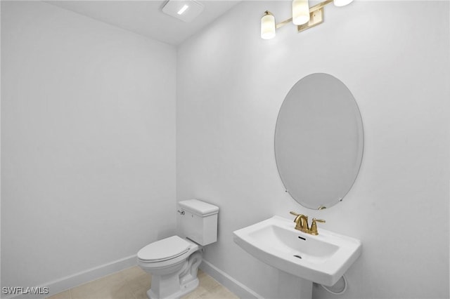 half bath with a sink, baseboards, tile patterned floors, and toilet
