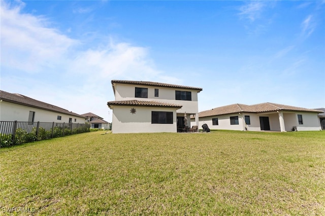 back of house with a yard, fence, a tiled roof, and stucco siding