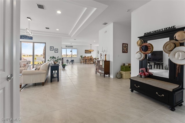 living area featuring a tray ceiling, visible vents, recessed lighting, and light tile patterned flooring