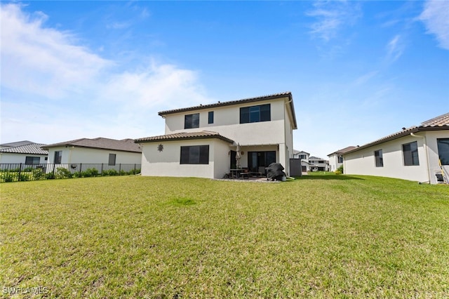 rear view of house with a yard, fence, a tiled roof, and stucco siding