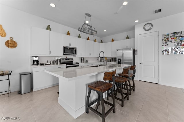 kitchen featuring visible vents, a breakfast bar area, appliances with stainless steel finishes, light countertops, and a sink