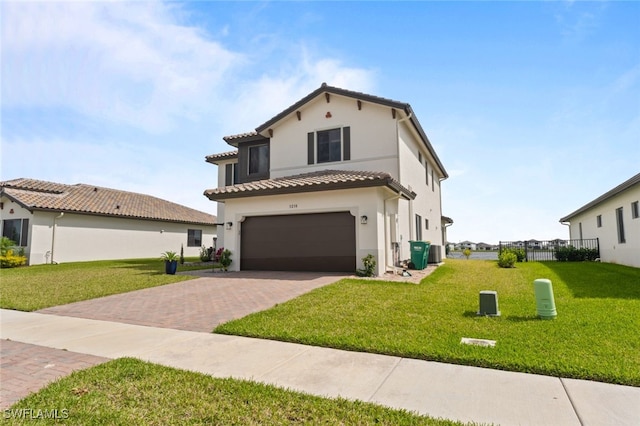 mediterranean / spanish home with decorative driveway, stucco siding, a garage, a tiled roof, and a front lawn