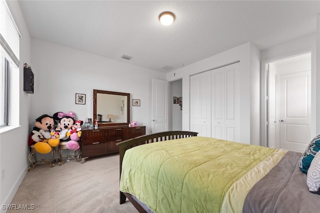 bedroom featuring a closet, light colored carpet, visible vents, and baseboards