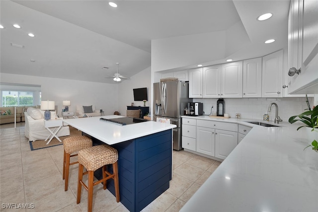 kitchen featuring a center island, stainless steel refrigerator with ice dispenser, open floor plan, vaulted ceiling, and a sink