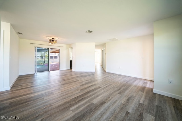 unfurnished living room featuring baseboards, visible vents, and dark wood-style flooring