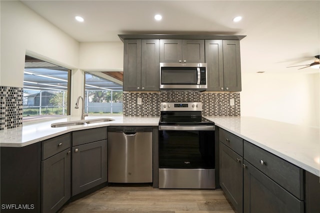 kitchen with recessed lighting, a sink, decorative backsplash, stainless steel appliances, and light wood-type flooring