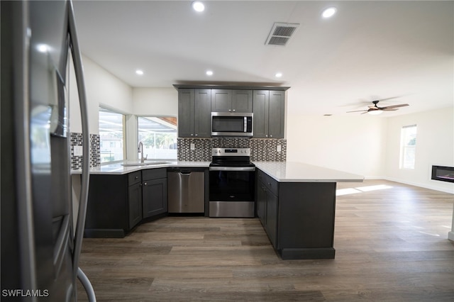 kitchen featuring tasteful backsplash, visible vents, a peninsula, stainless steel appliances, and a sink