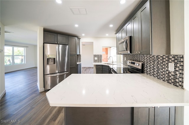 kitchen with visible vents, a peninsula, a sink, stainless steel appliances, and dark wood-type flooring