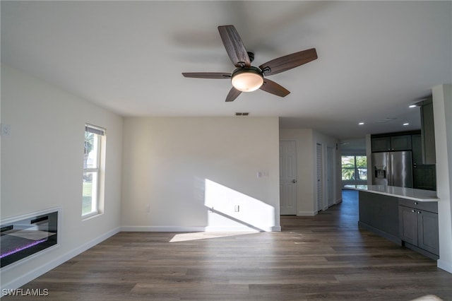 unfurnished living room featuring plenty of natural light, dark wood-style floors, and visible vents