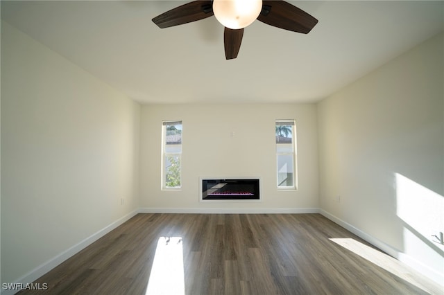 unfurnished living room with a glass covered fireplace, baseboards, and wood finished floors