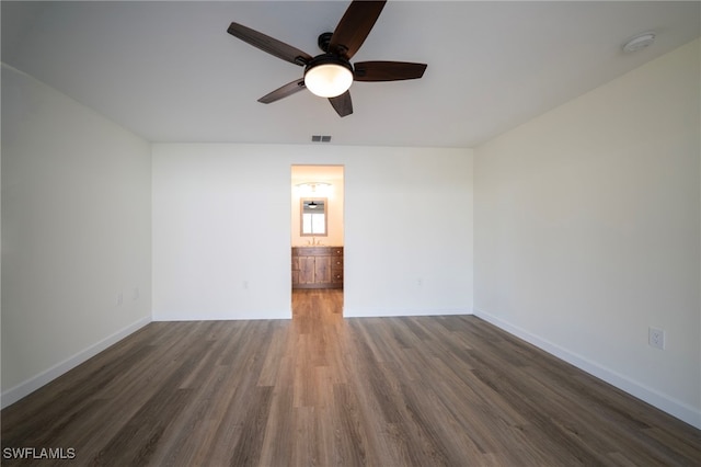 spare room featuring visible vents, baseboards, ceiling fan, and dark wood finished floors