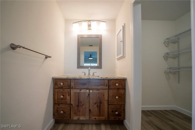 bathroom featuring baseboards, wood finished floors, and vanity