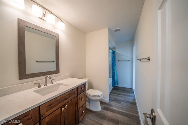 full bathroom with visible vents, toilet, wood finished floors, shower / bath combination with curtain, and vanity