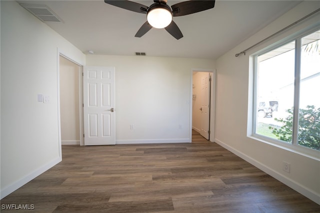 unfurnished room with baseboards, dark wood-style floors, visible vents, and ceiling fan