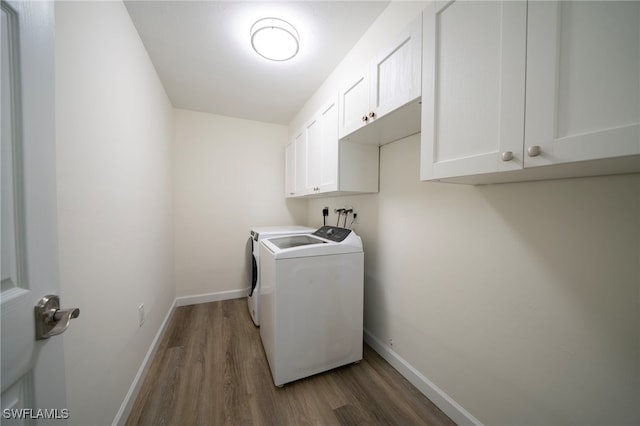 laundry area with baseboards, cabinet space, wood finished floors, and washer and clothes dryer