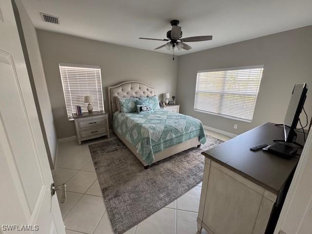 bedroom featuring light tile patterned floors, a ceiling fan, visible vents, and baseboards