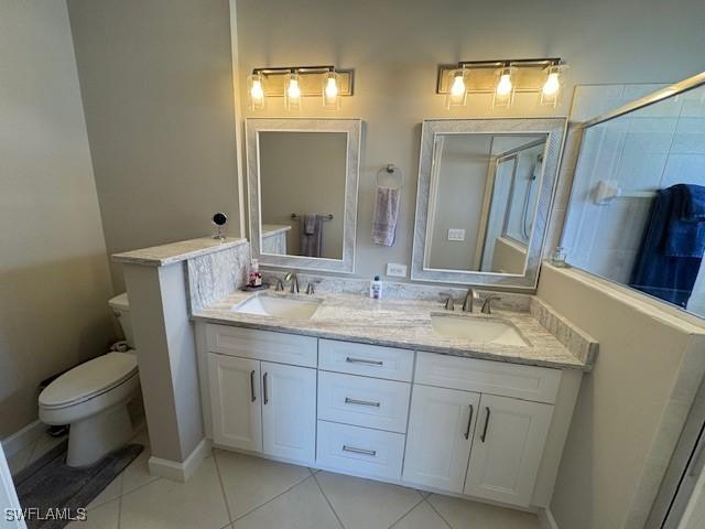 bathroom featuring tile patterned flooring, a sink, toilet, and double vanity