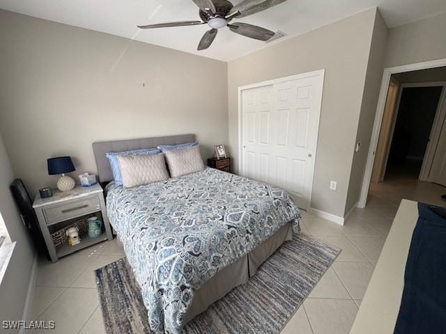 bedroom featuring light tile patterned floors, ceiling fan, baseboards, and a closet