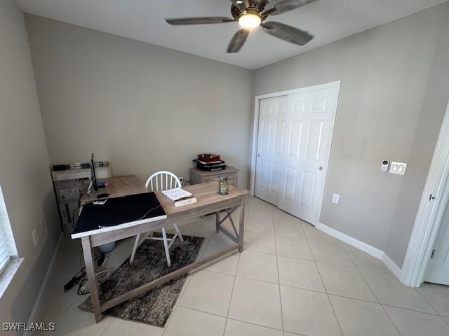 office featuring light tile patterned floors, a ceiling fan, and baseboards