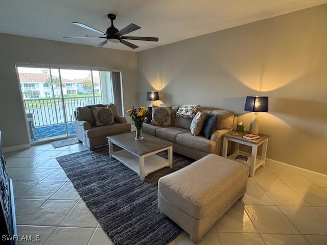 living area featuring light tile patterned floors, baseboards, and a ceiling fan