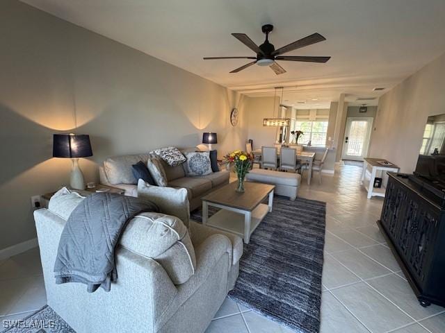 tiled living area with ceiling fan and baseboards