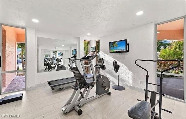 workout area featuring recessed lighting, a textured wall, and a textured ceiling