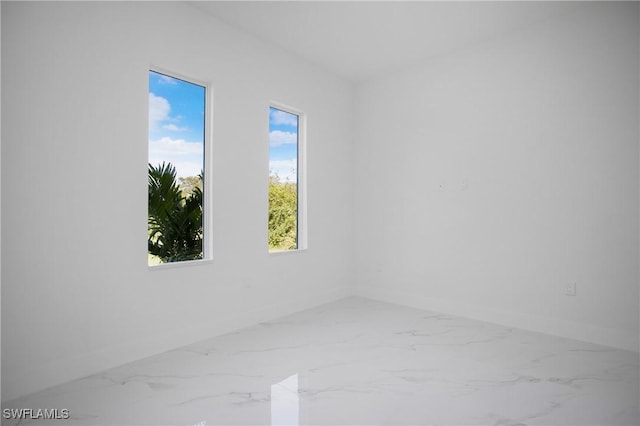 empty room featuring marble finish floor and baseboards