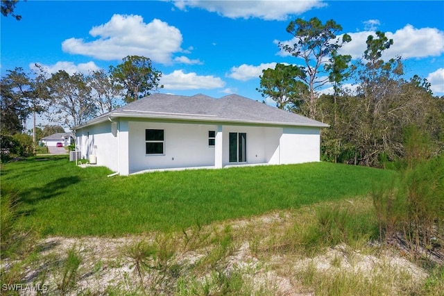 back of house featuring a lawn and stucco siding