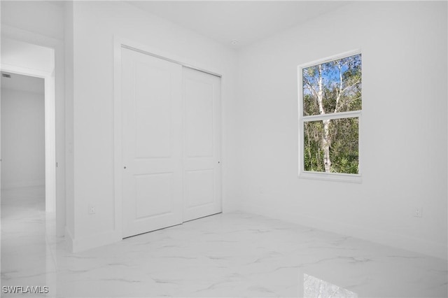 unfurnished bedroom with a closet and marble finish floor