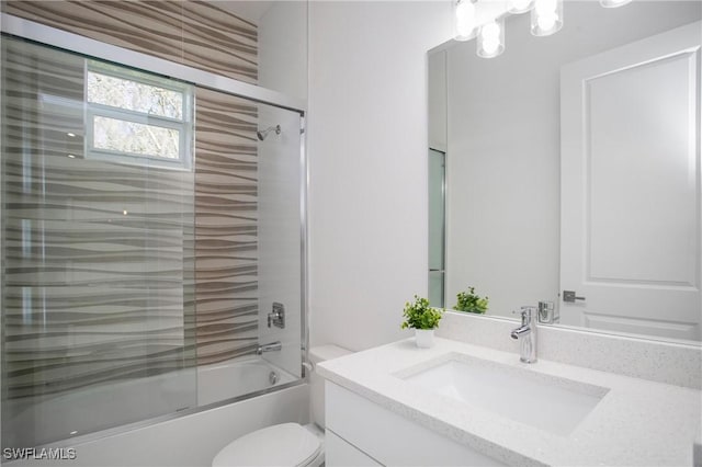 bathroom featuring toilet, combined bath / shower with glass door, and vanity