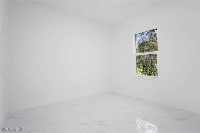 empty room featuring marble finish floor and baseboards