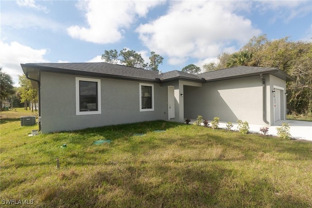 view of front of house with a garage, a front yard, cooling unit, and stucco siding