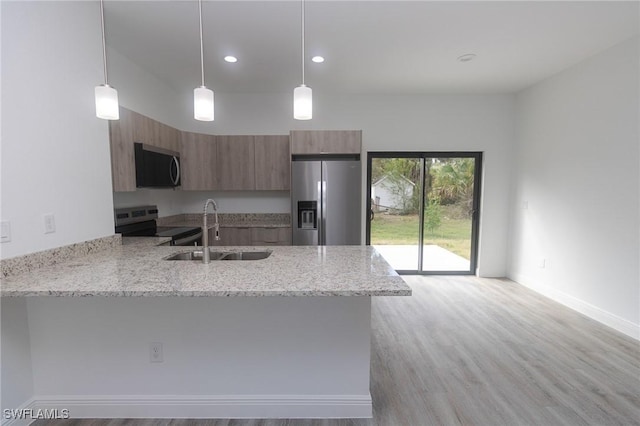 kitchen featuring brown cabinets, appliances with stainless steel finishes, a sink, modern cabinets, and a peninsula