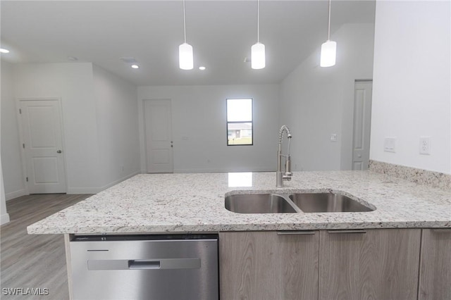 kitchen featuring light stone counters, light wood-style flooring, a sink, dishwasher, and pendant lighting