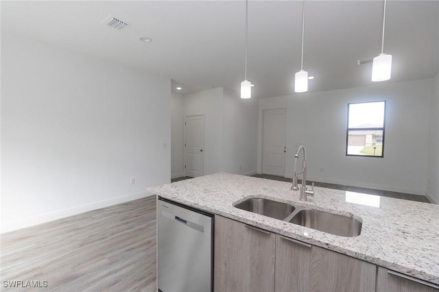 kitchen with light wood-type flooring, pendant lighting, dishwasher, and a sink