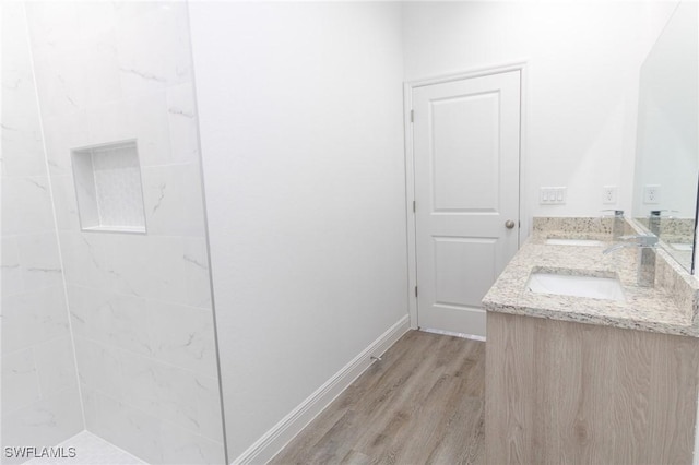 bathroom featuring double vanity, a sink, baseboards, and wood finished floors