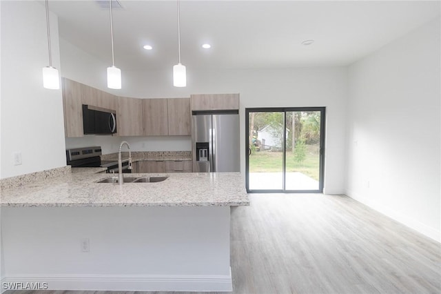 kitchen with modern cabinets, appliances with stainless steel finishes, a peninsula, light stone countertops, and a sink